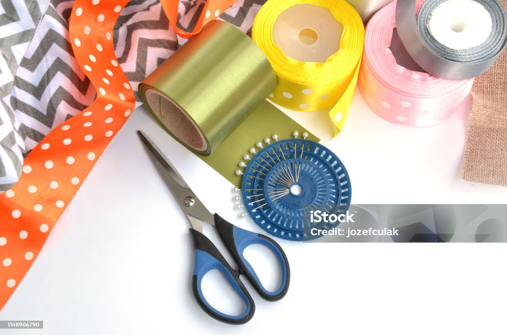 Flat lay made by color ribbons, scissors and pins on white background Above Stock Photo