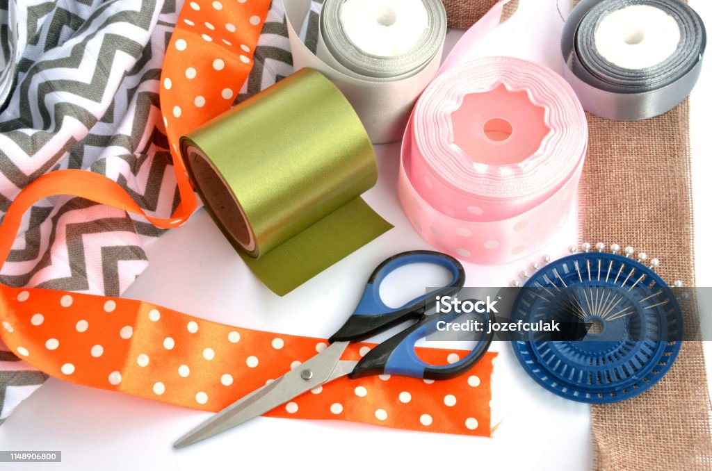 Flat lay made by color ribbons, scissors and pins on white background Above Stock Photo