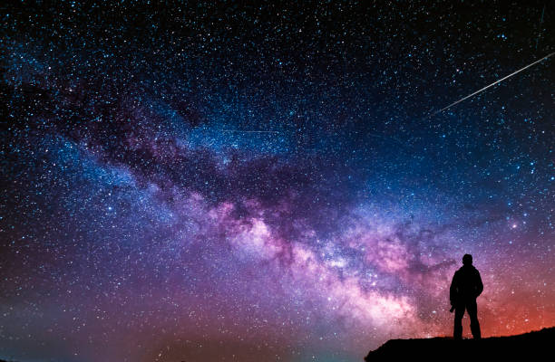 hermosa noche estrellada, silueta de hombre con una cámara mirando la galaxia de la vía láctea. - exposición larga fotos fotografías e imágenes de stock