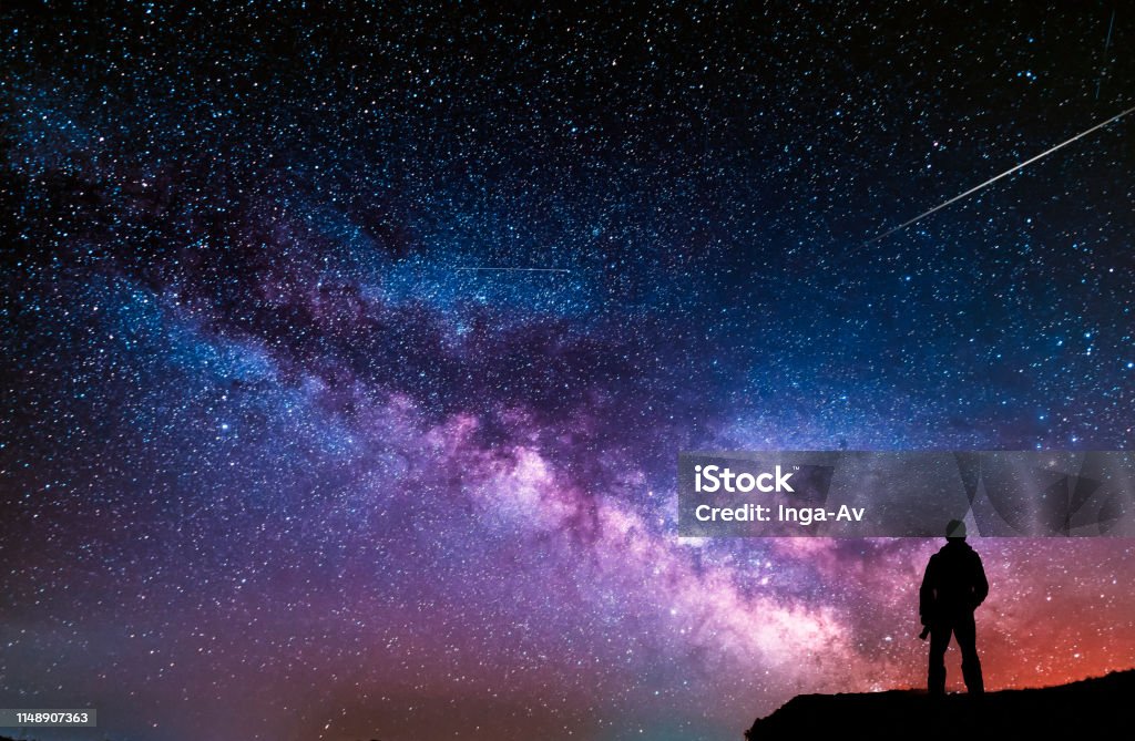 Beautiful starry night, man silhouette with a camera looking at the Milky Way galaxy. Star - Space Stock Photo