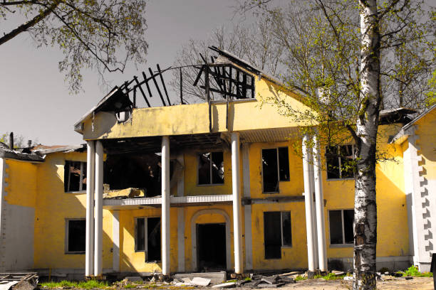 quemado después de fuego gran casa de campo con un techo dañado colapsado contra un cielo gris. incendiada una gran casa de campo con un tejado dañado contra un cielo gris - house farm brick chimney fotografías e imágenes de stock