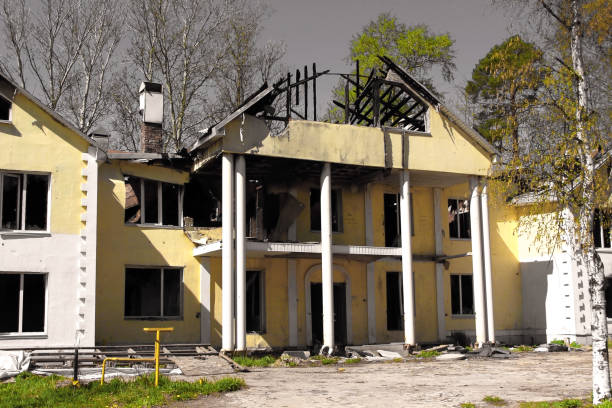 quemado después de fuego gran casa de campo con un techo dañado colapsado contra un cielo gris. incendiada una gran casa de campo con un tejado dañado contra un cielo gris - house farm brick chimney fotografías e imágenes de stock