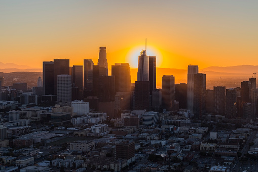 Dawn aerial view of rising sun behind downtown Los Angeles in Southern California.