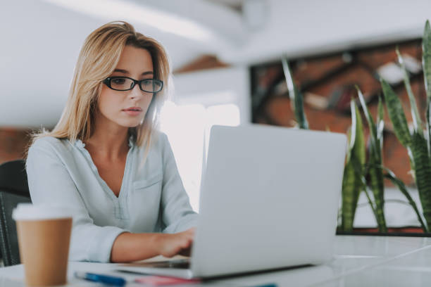 istock Fair haired woman sitting in the office and using modern laptop 1148917402
