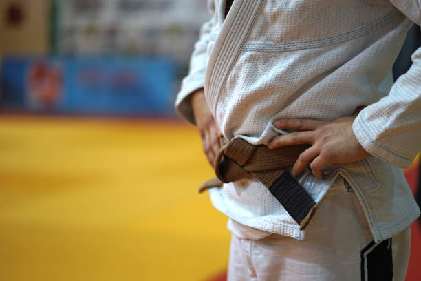 nahaufnahme auf dem mittelteil eines bjj jiu-jitsu brasilianischen jiujitsu fighter braunen gürtel in einem weißen gi kimono wartet auf den kampf beim turnier - ju jitsu stock-fotos und bilder