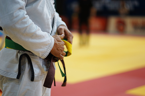 Fighter tightening karate belt on black background