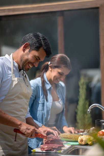 istock Happy latin amerivcan couple preparing a barbecue having fun smiling 1148934342