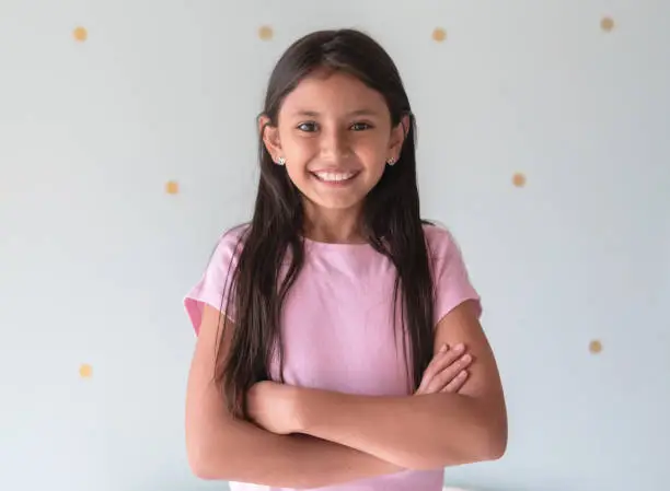 Photo of Portrait of beautiful latin american little girl facing camera smiling with arms crossed