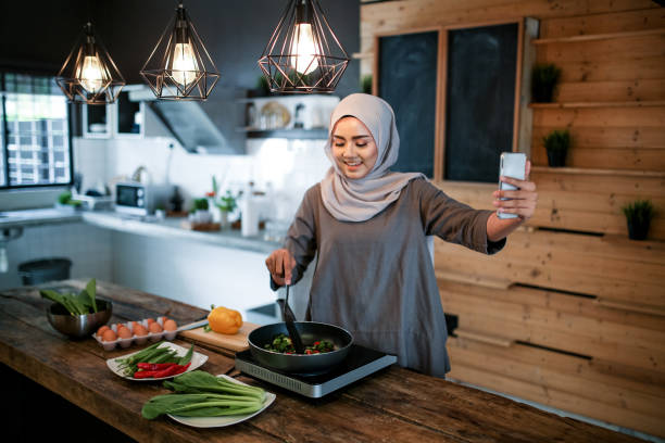 istock One women looking at phone while cooking 1148937541
