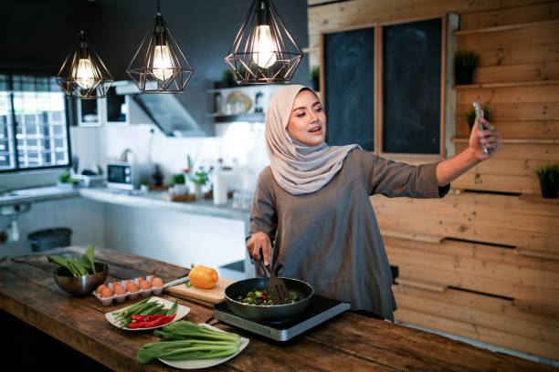 istock One women looking at phone while cooking 1148937544