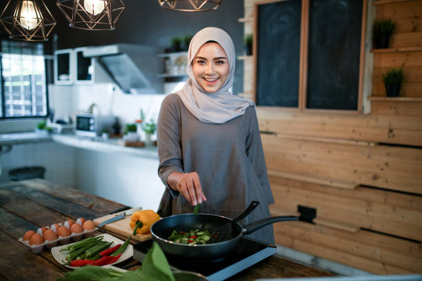 istock One women looking at phone while cooking 1148937548