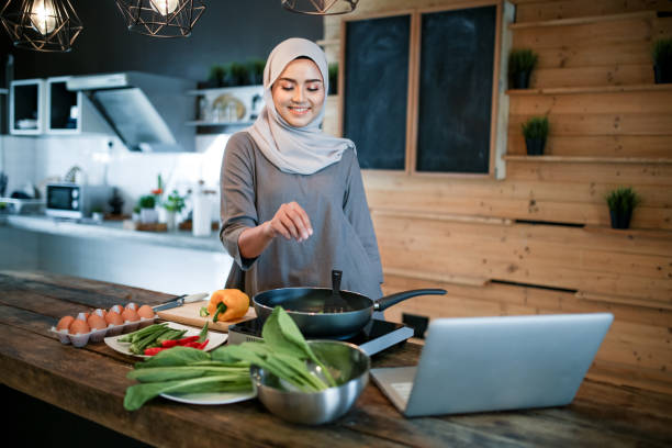 istock One women cooking in kitchen with laptop 1148937549