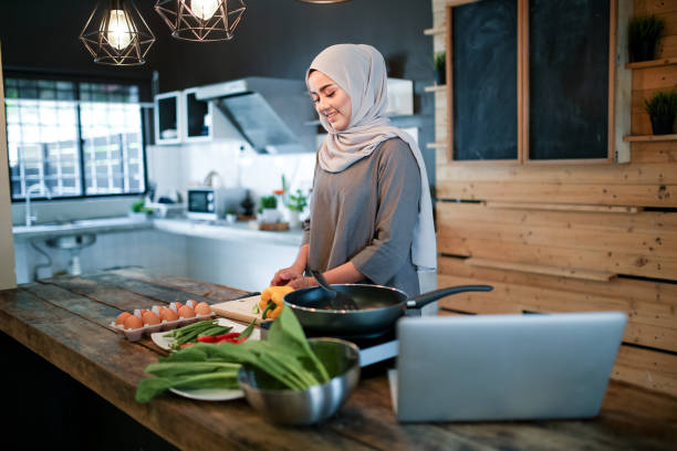 istock One women cooking in kitchen with laptop 1148937558