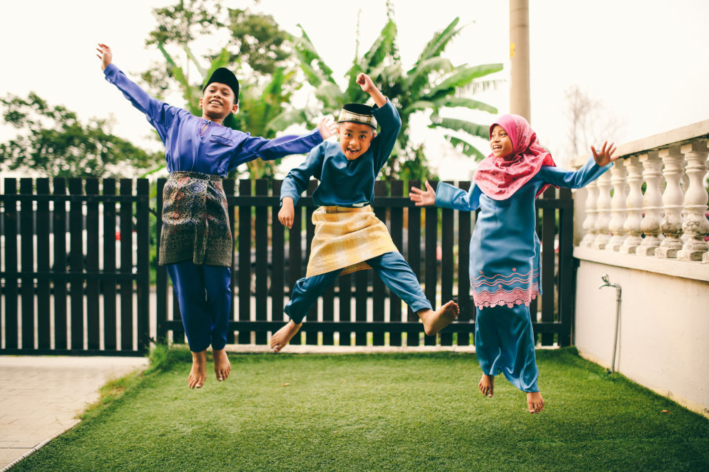 Three sibling playing in front of house during eid celebration in Malaysia