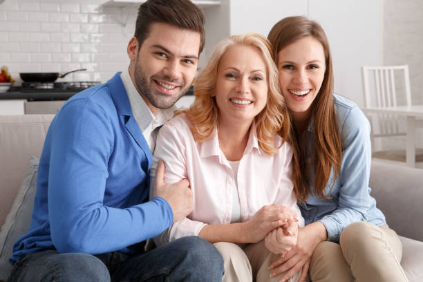 Young family with mother-in-law at home weekend hugging smiling stock photo