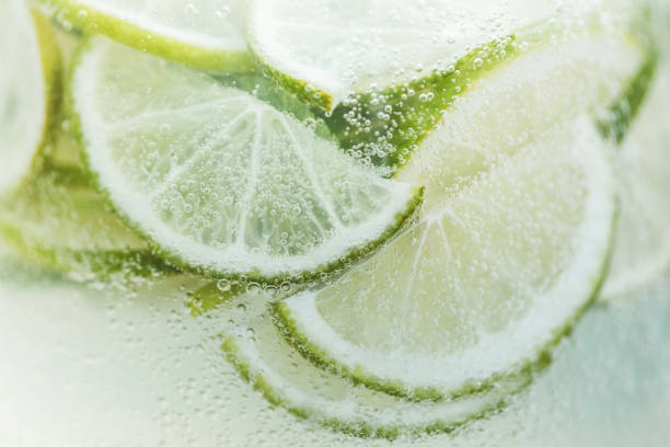 Close-up fresh lemon slices in cold lemonade with bubbles stock photo