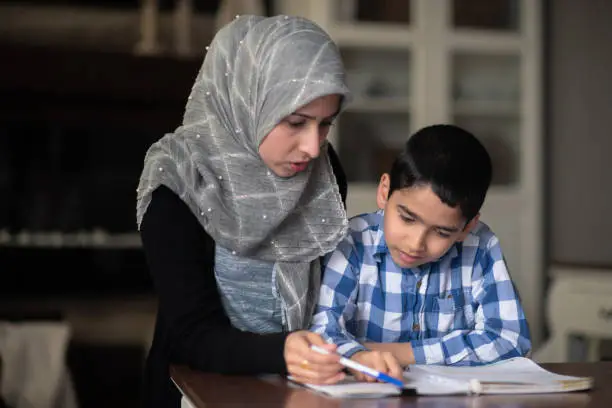 Photo of Ethnic mother helping her son with homework