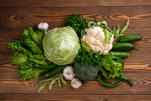 Healthy vegan food assortment. Organic vegetarian food ingredients vegetables on green background, copy space, top view. Clean vegan eating and detox concept.