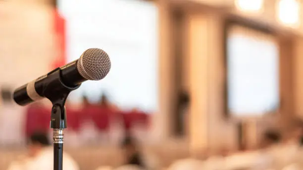 Photo of Microphone voice speaker in business seminar, speech presentation, townhall meeting, lecture hall or conference room in corporate or community event for host or public hearing