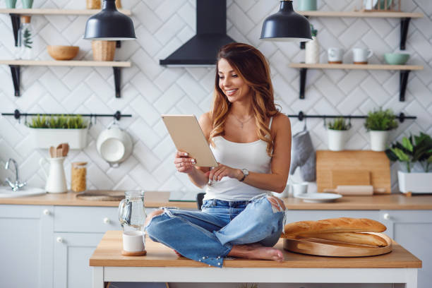 istock Beautiful woman uses tablet computer while sitting on the table on the cozy kitchen in the morning at home. 1148940907