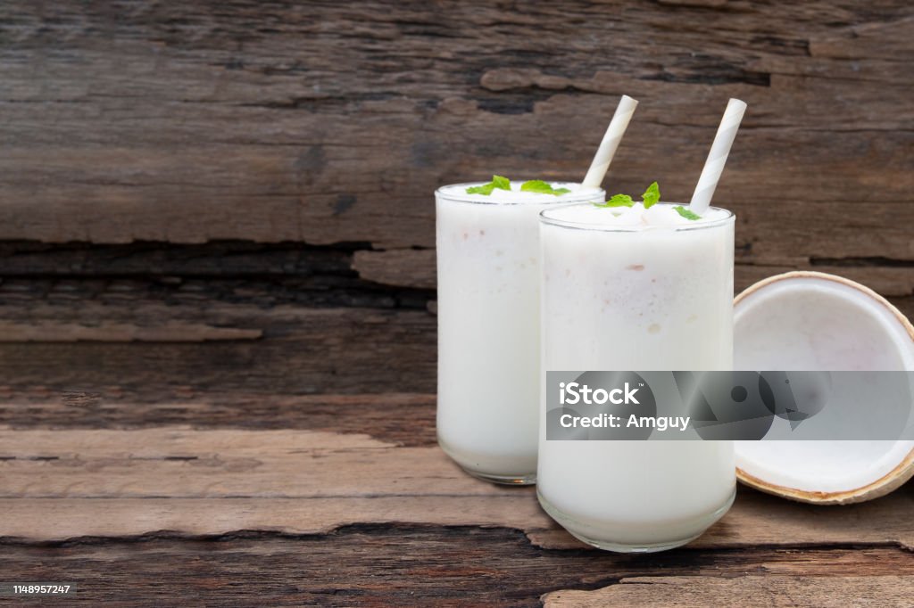 Coconut smoothies white fruit juice milkshake blend beverage healthy high protein the taste yummy In glass drink episode morning on a wooden background. Coconut Stock Photo