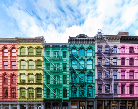 Rainbow colored block of old buildings in the SoHo neighborhood of Manhattan in New York City with blue sky background above