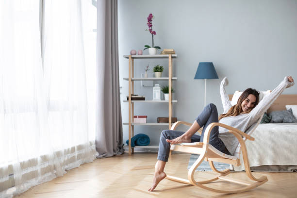 glückliche frau ruht gemütlich auf dem modernen stuhl im wohnzimmer zu hause. - comfortably stock-fotos und bilder
