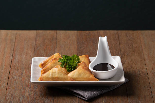 istock Delicios dish, Fried samosas in white plate with chocolate dipping sauce on wooden table background 1148977659