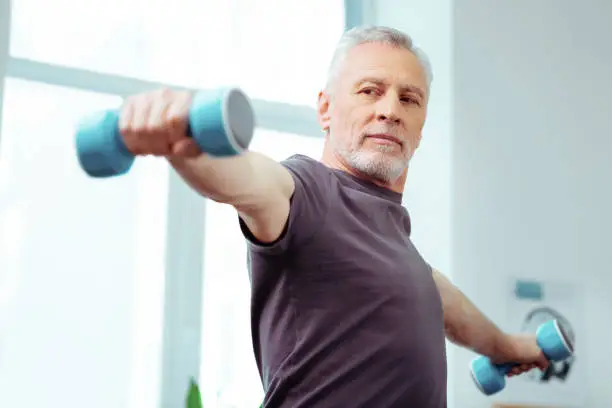 Photo of Strong fit aged man looking at his hands