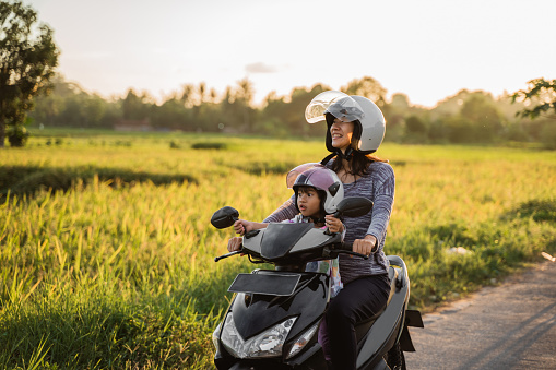 mom and child enjoy riding motorcycle scooter togehter