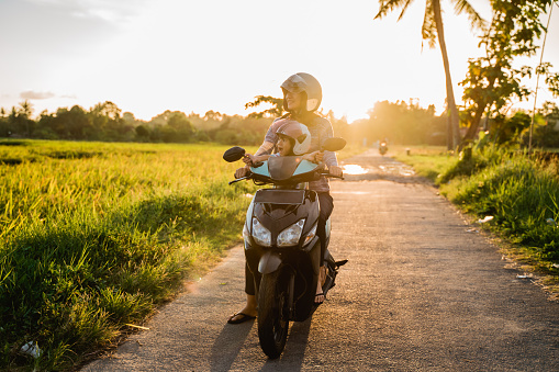 mom and her child enjoy riding motorcycle scooter in country ride road