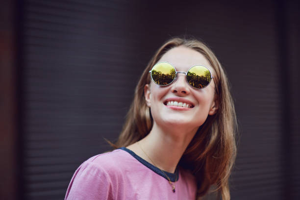 istock Blond girl in sunglasses smiling on a striped  background. 1148980159
