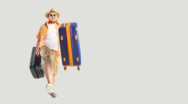istock Fat funny man a suitcase smiling goes on a gray background. 1148981717