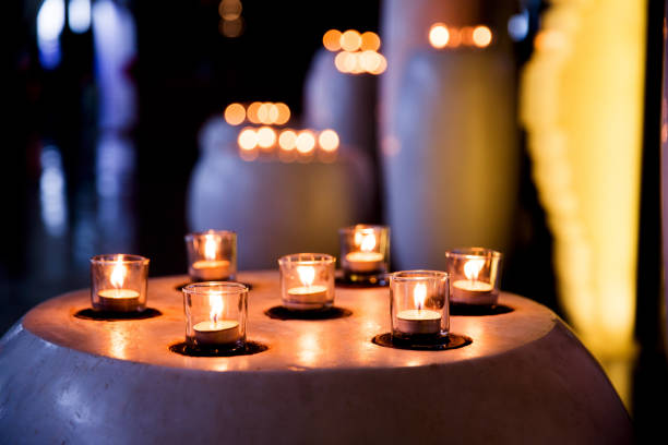 Flame of many candles burning on blurred lights background. Holiday concept.