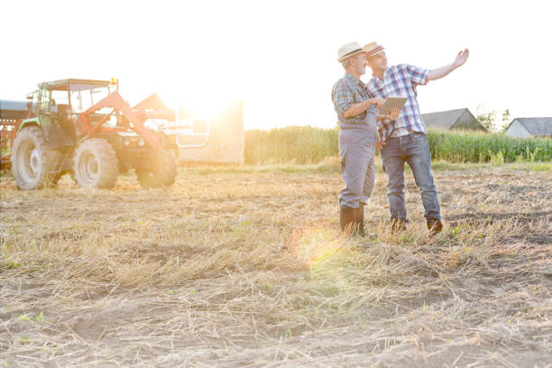istock Farmers talking while using digital tablet at farm on sunny day 1148985705