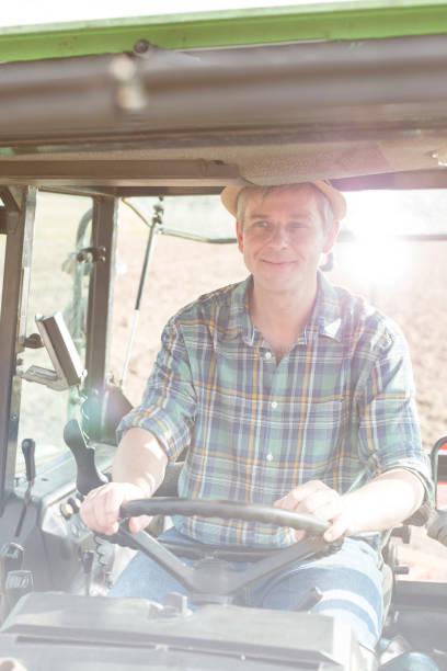 istock Smiling confident mature farmer driving tractor at farm 1148985712