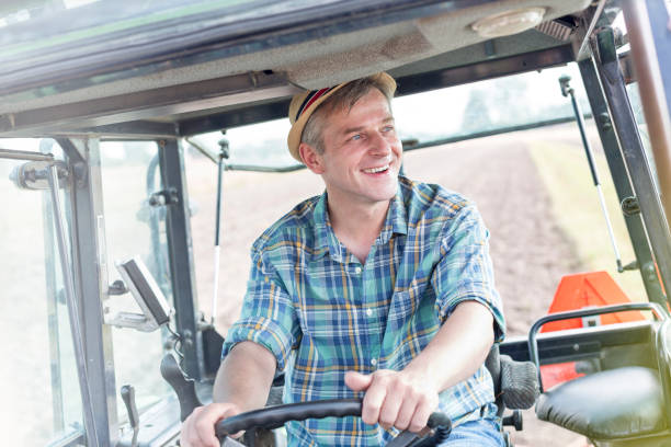 istock Smiling confident farmer driving tractor at farm 1148987009