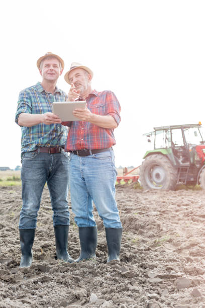 istock Farmers discussing over digital tablet at farm against sky 1148987013