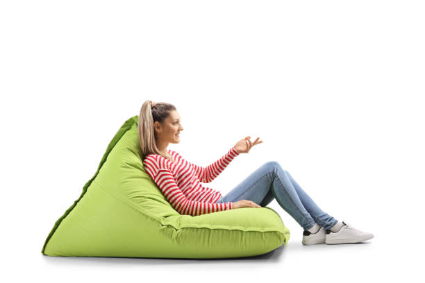 istock Young woman sitting on a bean bag and gesturing with hand 1148988249