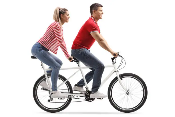 Full length shot of a young man and woman riding a tandem bicycle isolated on white background