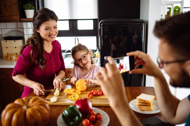 istock Father photographing family at table in kitchen 1148989712