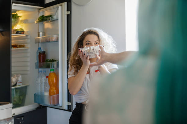 blond young woman taking a bowl of mushrooms with surprise - three different refrigerators imagens e fotografias de stock