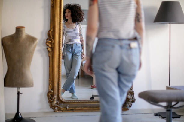 reflection of young tattooed woman in the mirror - mirror women looking reflection imagens e fotografias de stock