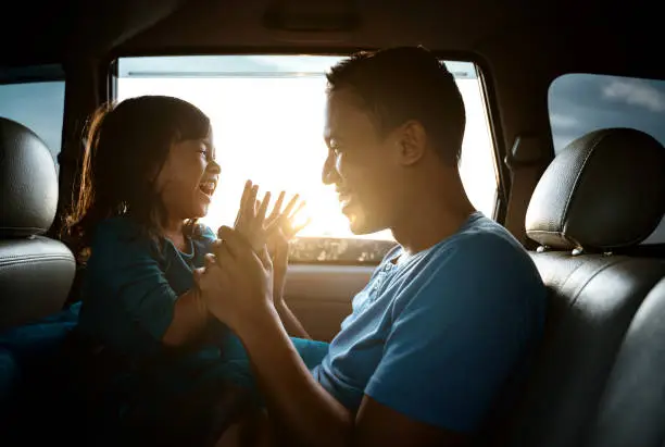 Photo of asian daughter with father in the car playing