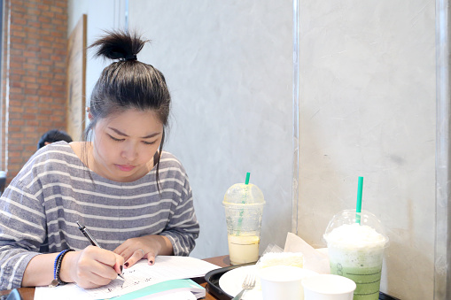 The Asian woman learning japanese language in the coffee shop.