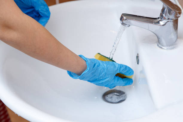 istock women's hands in blue gloves clean the sink 1148997069