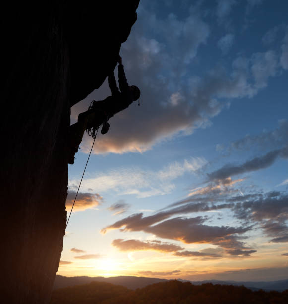 istock Athletic silhouette rock climbing. Sunrise sky with clouds. Copy space. Side view. Success, leading, chievements concept 1148998560