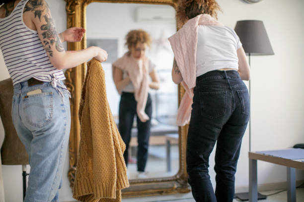 istock Young women trying on sweaters in front of the mirror 1148998866