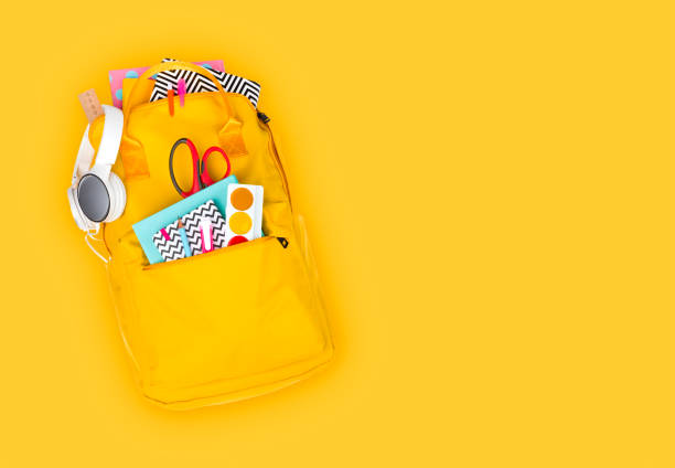 рюкзак со школьными принадлежностями и аксес�суарами изолирован на желтом фоне - scissors red school supplies isolated стоковые фото и изображения