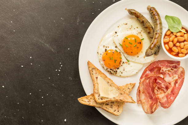 istock Full english breakfast on white plate, black background. 1149000391